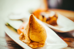 Two white plates containing freshly made samosas, a favorite of Indian cuisine.